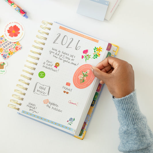 Floral sticker being placed on planner